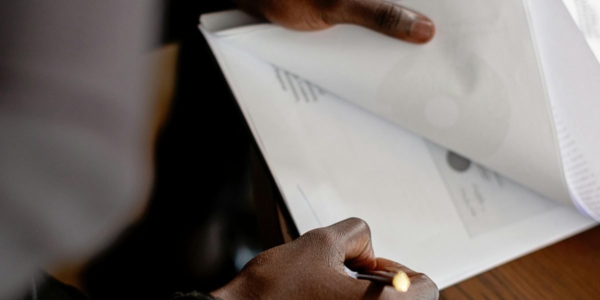 A business professional meticulously reviewing documents or contracts, symbolising the careful consideration required when choosing a hosting provider.