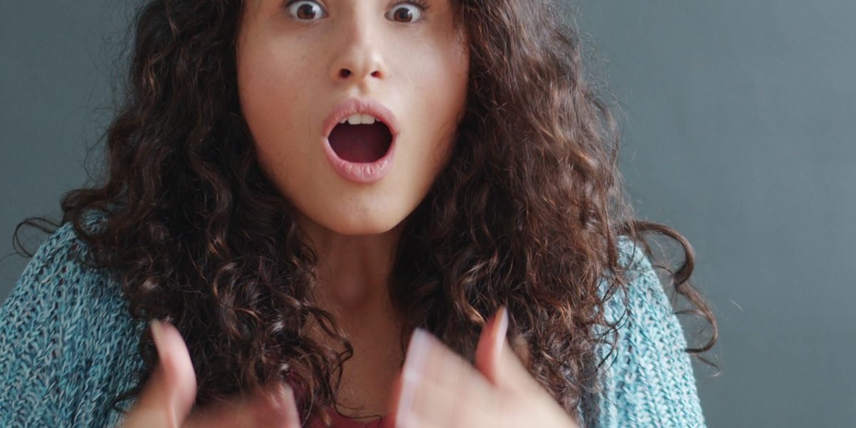 A person looks surprised and concerned while reviewing documents, reflecting the unexpected costs often associated with cheap domain hosting plans.