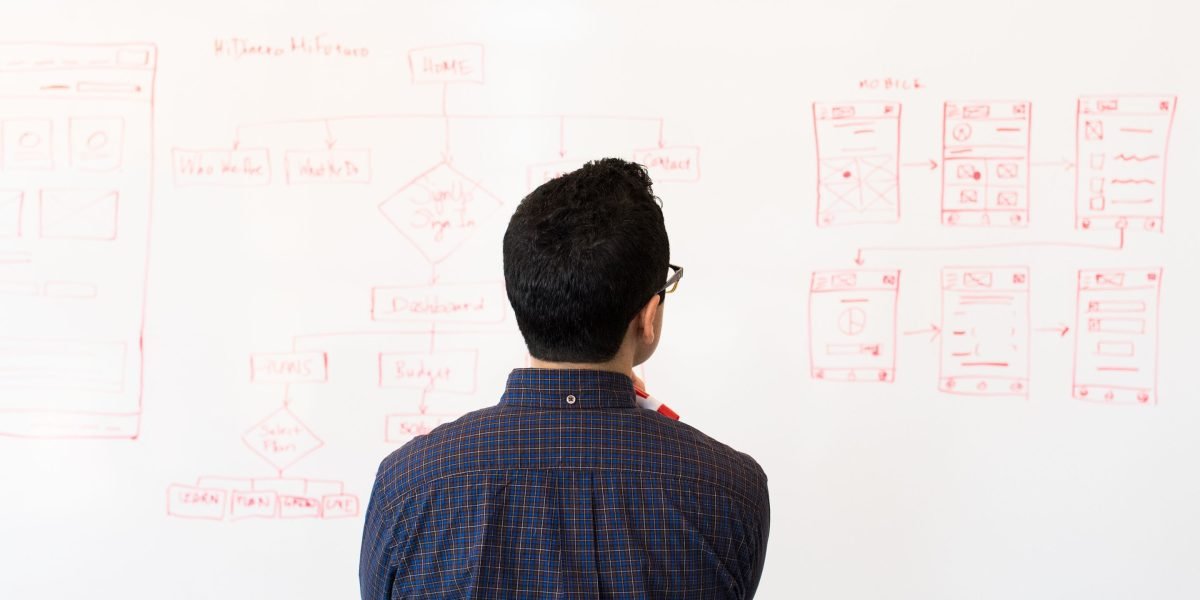 A person looking thoughtfully at a whiteboard with graphs and notes, representing strategic planning for business and website scalability.