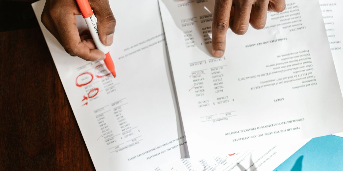 A person meticulously reviews budget documents or financial statements, emphasizing the importance of identifying and accounting for all potential hidden fees.
