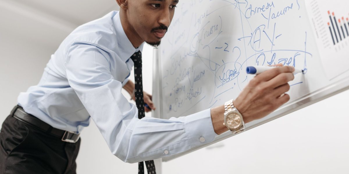 A person carefully considering different domain name extensions (.com, .net, .org, .shop) on a whiteboard.