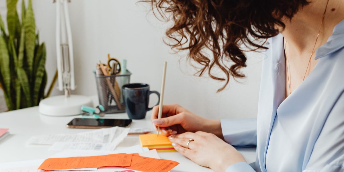 A small business owner sits at a desk, contemplating financial documents and a laptop, reflecting the challenge of managing a budget for online services.
