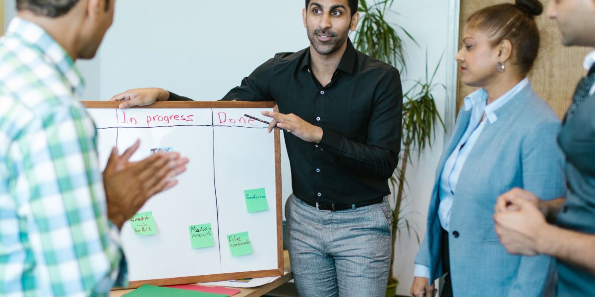 A diverse team collaborating around a whiteboard, actively discussing and planning strategies, illustrating teamwork and problem-solving in a business setting.