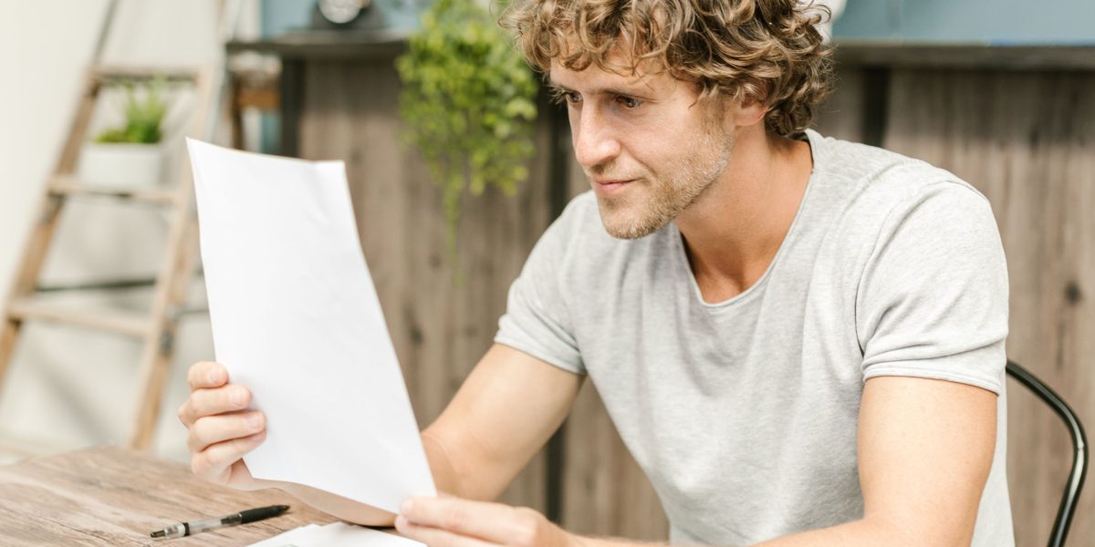 A person looking intently and with a slight frown at documents, interpreting complex data or results.