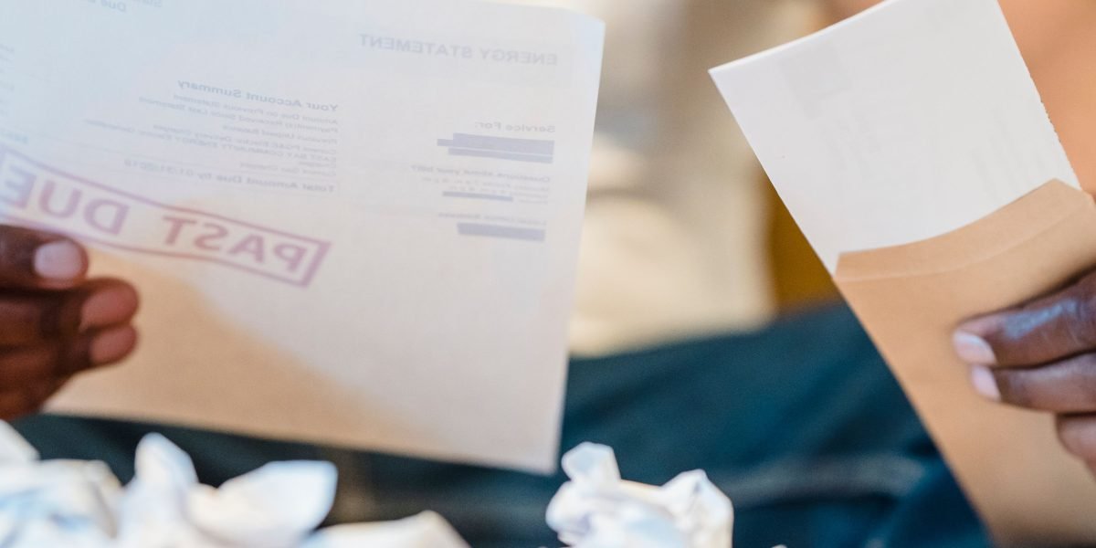 A small business owner thoughtfully reviewing budget sheets, contemplating website hosting expenditures.