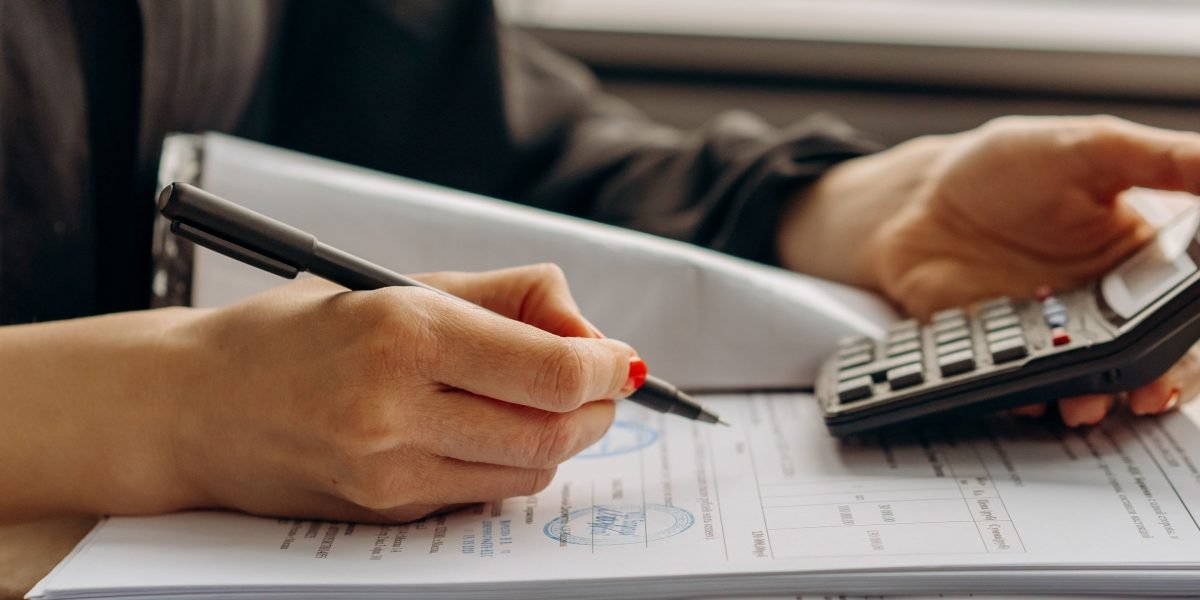 An individual carefully reviewing financial documents and planning their business budget, emphasizing cost-effectiveness.